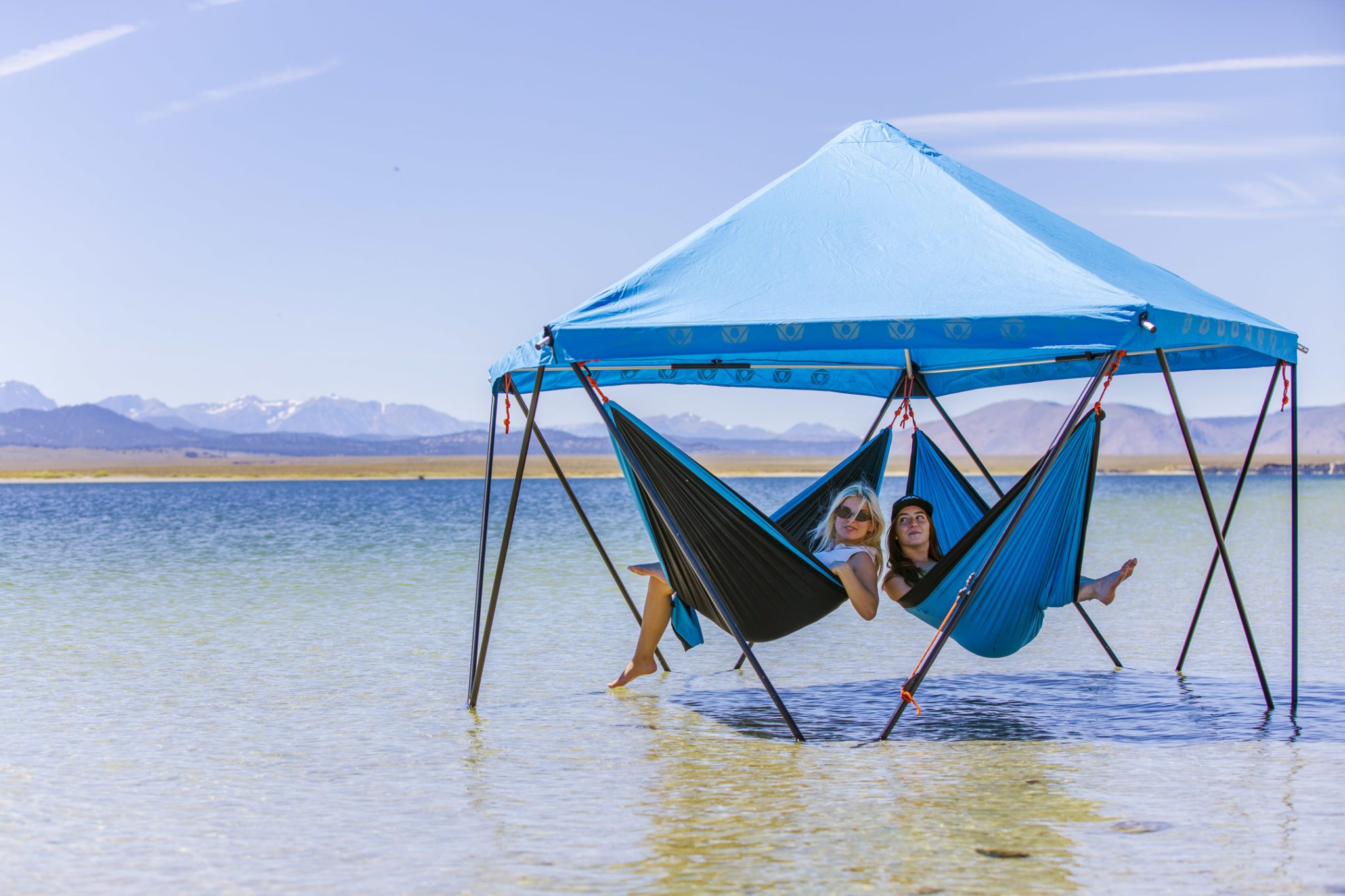iDome hammock tent and dome tent setup featuring a couple enjoying a relaxing nap on the beach.